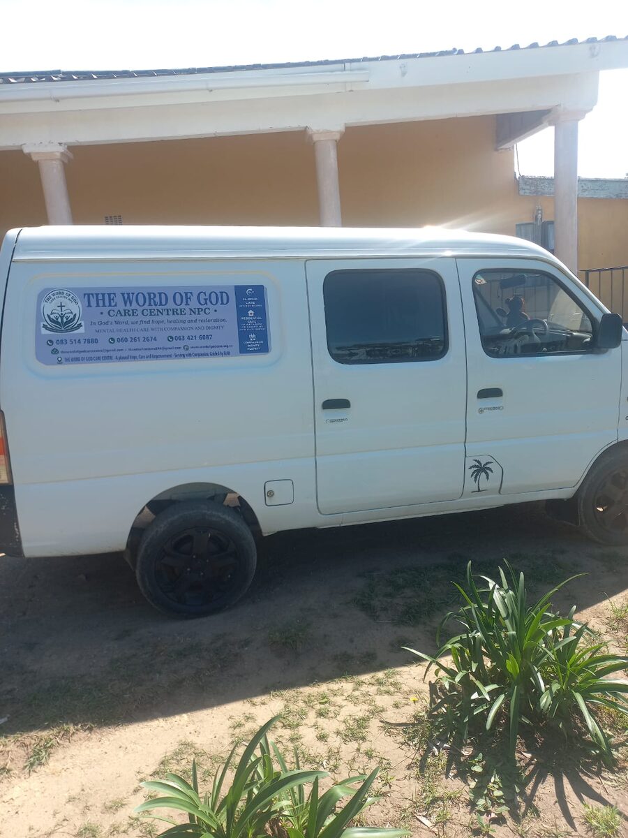 The Word of God Care Centre's white transport van parked outside the ochre building