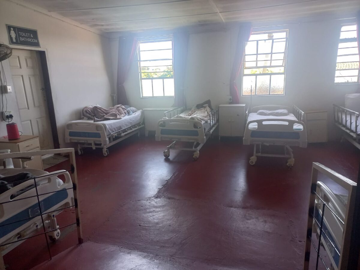 A quiet resident ward at the care centre with beds made up and polished red floors